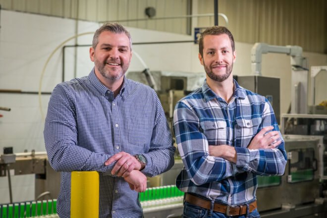 two men in plaid shirts standing in a factory
