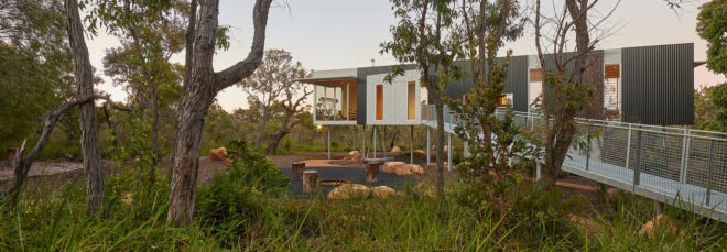 modern home on stilts surrounded by forest at dusk