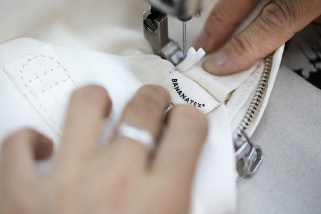 person sewing a tag onto a white bag