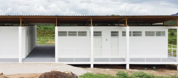white beekeepers workshop surrounded by grass