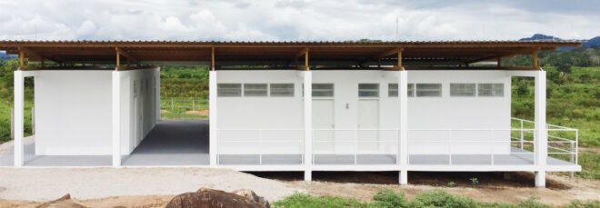 white beekeepers workshop surrounded by grass