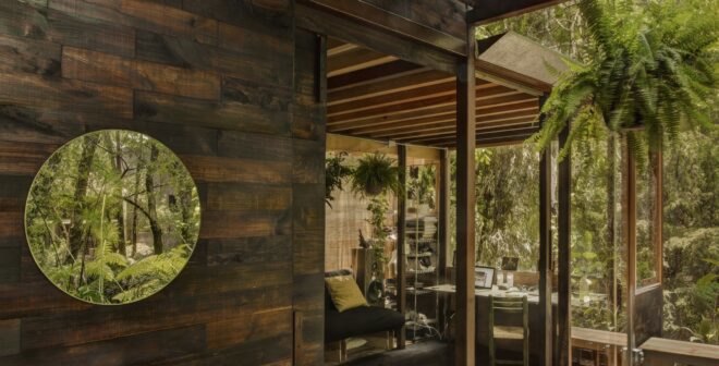 view of the interior of the home through large glass windows surrounded by trees and plants