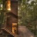 wood treehouse with wood spiraled stairs surrounded by forest with interior lights illuminating the home
