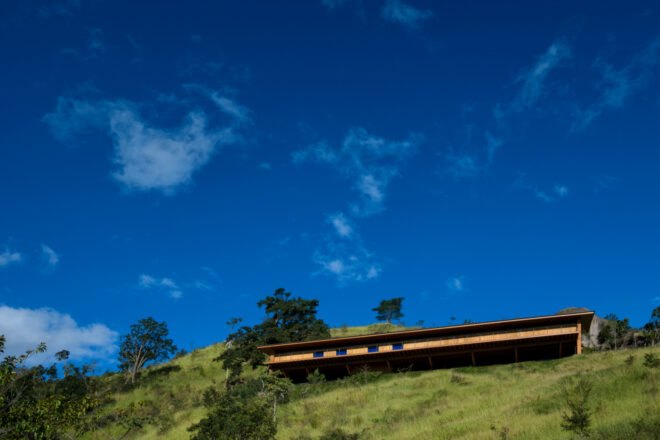 elongated home with large wooden deck surrounded by greenery
