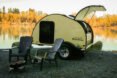 yellow teardrop camper with back hatch open and two seats out front