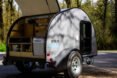 white teardrop camper with back door lifted open to reveal a kitchen