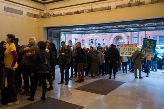 climate activists stand in line holding signs