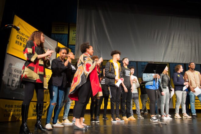 group of youth activists stand on stage during rally