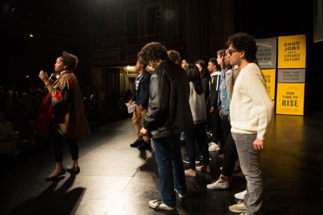 group of youth activists stand on stage during rally