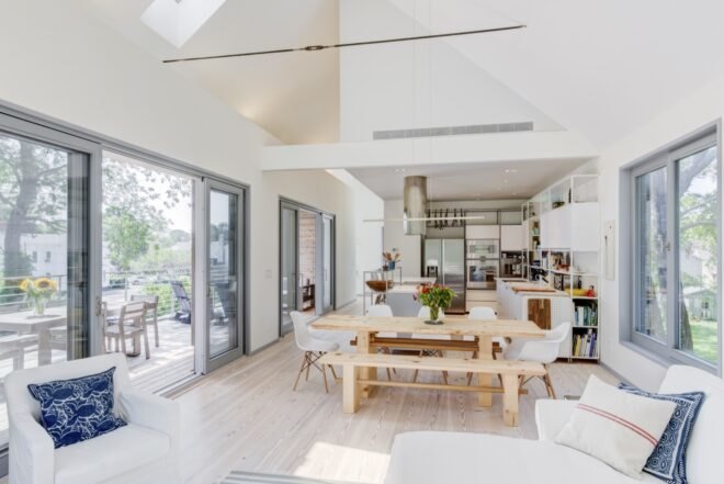 open floor plan with white couch, wood dining table and white kitchen