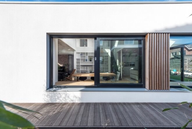 white home with large window facing the outdoor wooden deck