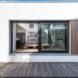 white home with large window facing the outdoor wooden deck