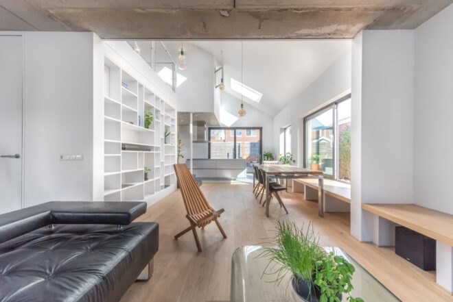 interior of home with wooden chairs and black couch surrounded with white walls and large windows