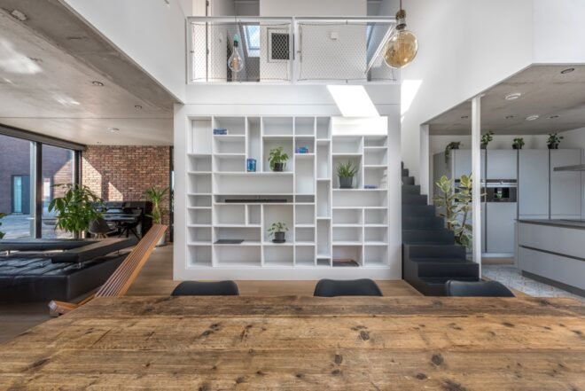 wooden floors in lower level of the home with nearby staircase and white bookshelf