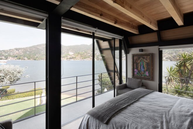 bedroom with glass walls revealing lakeside views
