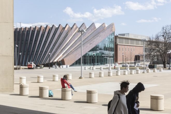 people walking outside a copper and glass building