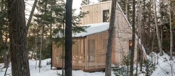 wood A-frame micro home in snowy forest