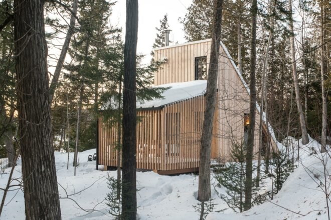 wood A-frame micro home in snowy forest