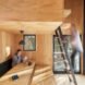 one person sitting at table reading a book and another person climbing ladder up to a loft