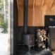 black wood-burning stove with stack of firewood next to it