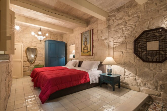 spacious guest room with two beds with red covers