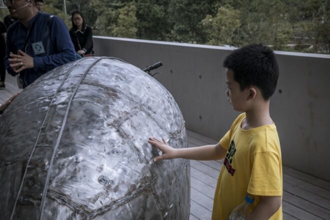 kid touching metal exterior of tiny library
