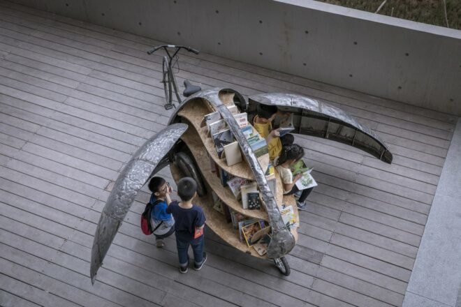kids reading books from a small library cart