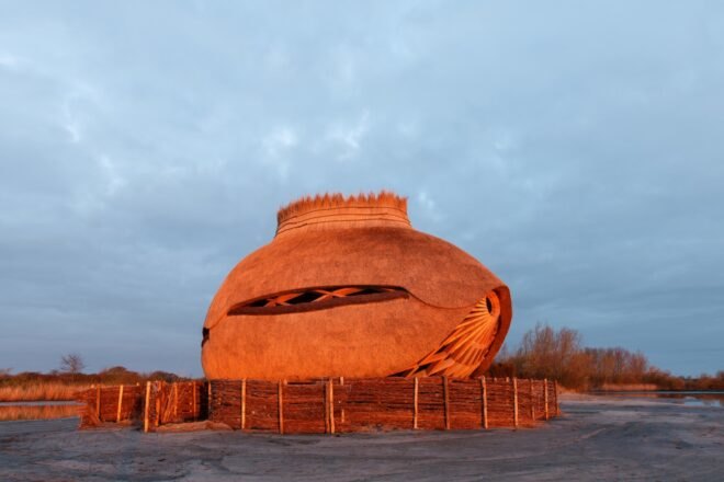 oval wooden bird observatory lit up at dusk