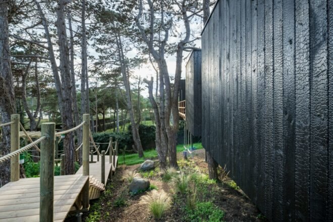 long wood walkway leading to black timber home