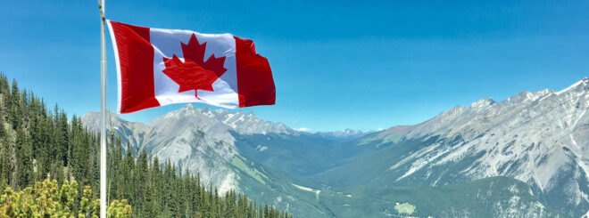 Canadian flag with green forest and mountains in background