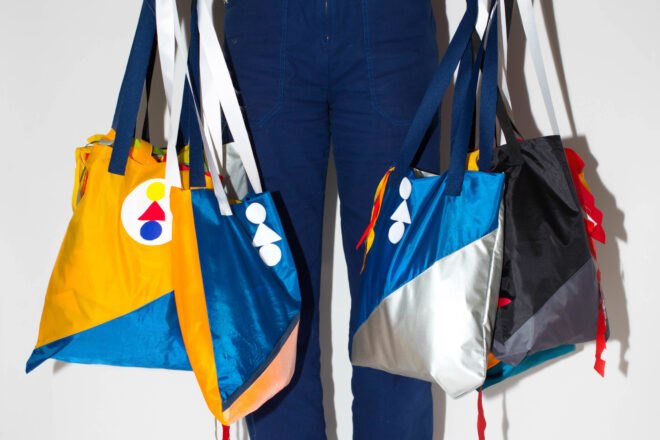 person holding several colorful recycled fabric bags