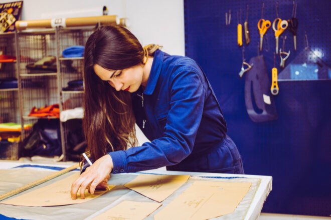 person making clothing patterns on a work table