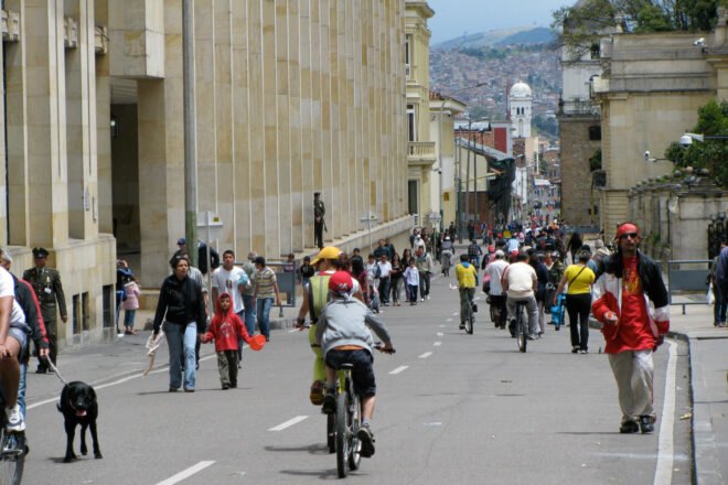 people biking and walking on a road near buildings