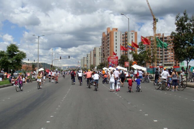 people gathered around tall, colorful flags in the street