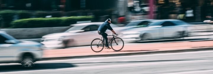 person riding bike as cars drive past
