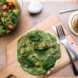 homemade pizza with green sauce on a wood board