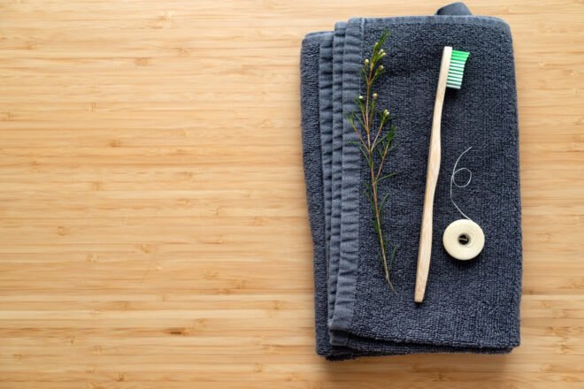 bamboo toothbrush and natural floss on blue washcloth