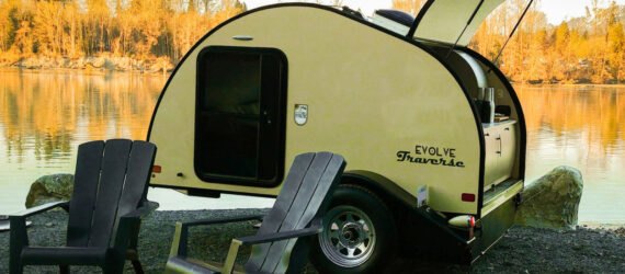 yellow teardrop camper with back hatch open and two seats out front