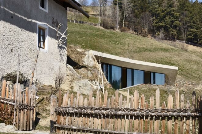 rustic old house beside a modern partially underground house