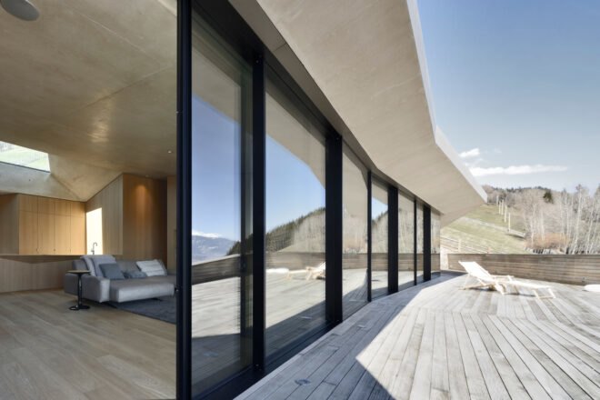 house with glass wall open to wood deck