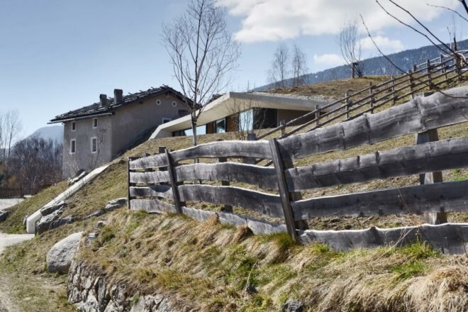 rustic wood fence outside concrete home buried in a hill