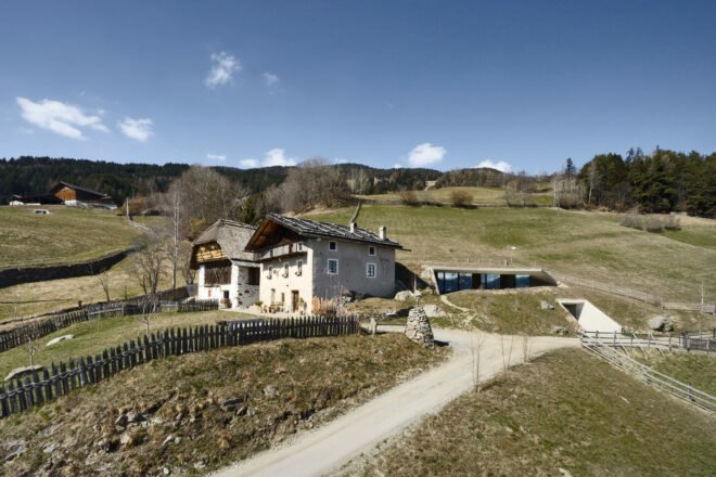 old farmhouse next to modern underground dwelling