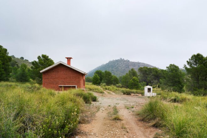 small brick home with gabled roof on grassy lot