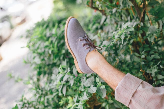 leg sticking out wearing a gray vegan oxford shoe