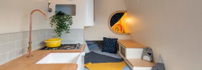 interior of camper van with gray day bed, a sleeping pod and yellow accents throughout