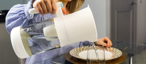person filling glass with water from pitcher