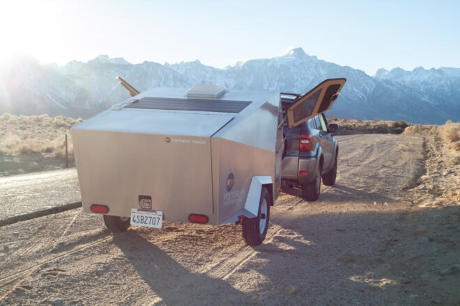 geometric metal trailer with open doors parked in front of mountains