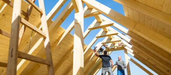 two men build a roof on a house