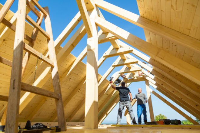 two men build a roof on a house
