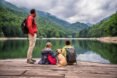family sits on a dock near a lake with dog